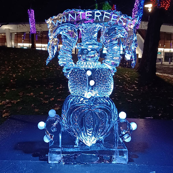 An ice sculpture bathed in blue light stands outdoors.